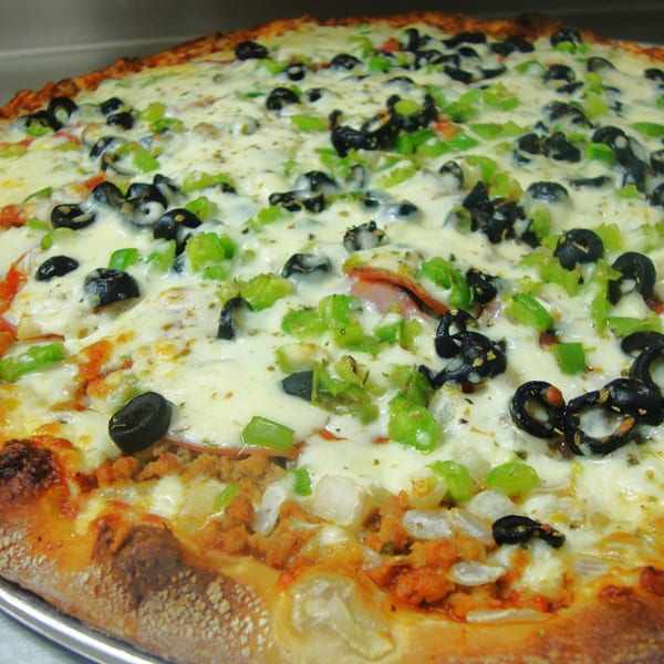 Close-up of a Harris Pizza with melted cheese, black olives, green peppers, and sausage.