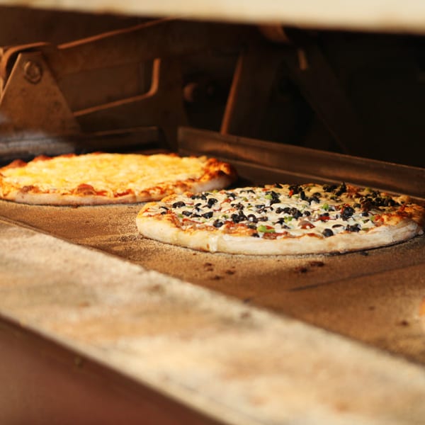 Two Harris pizzas, one cheese and one with olives and peppers, baking in a hot oven.