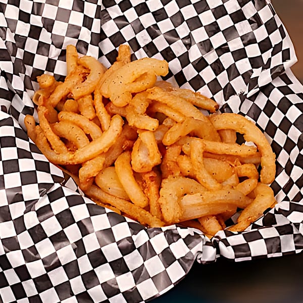 Crispy seasoned curly fries served in a black and white checkered paper basket.