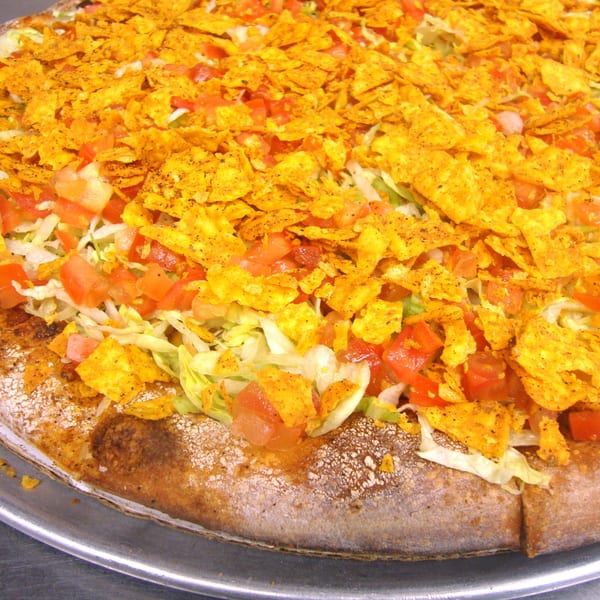Harris Pizza's taco pizza, topped with shredded lettuce, diced tomatoes, and crushed nacho chips.
