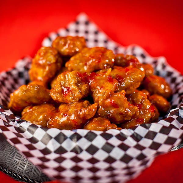 Harris Pizza's boneless wings, coated in a sweet and spicy sauce, served in a checkered basket.