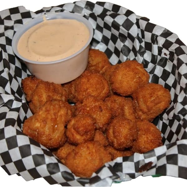 A basket of golden-brown fried mushrooms with a side of dipping sauce, from Harris Pizza.
